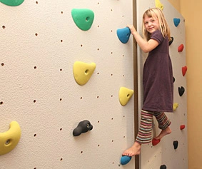 therapeuthische Kletterwand mit  Griffen und einer jungen Klettermaus
